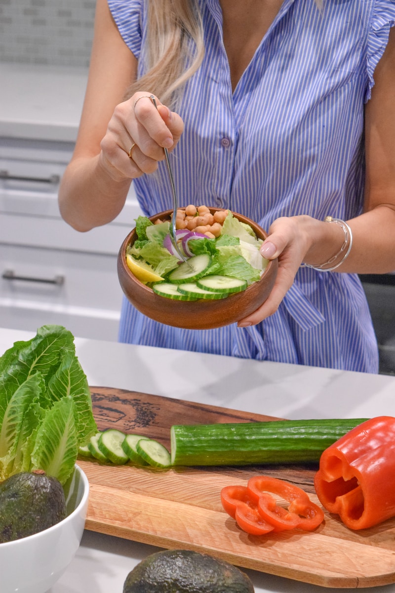 person holding green vegetable on brown ceramic plate